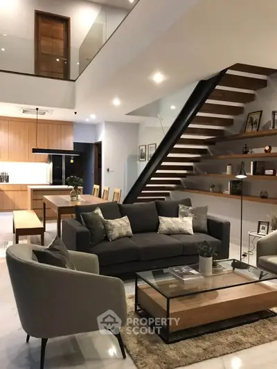 Modern living room with stylish furniture and open staircase in luxury home
