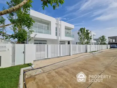 Modern white two-story house with large windows and gated driveway