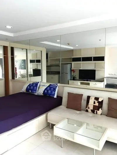 Modern studio apartment with mirrored walls and sleek furnishings, featuring a cozy bed and stylish living area.