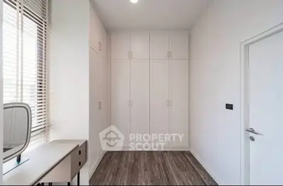 Spacious modern bedroom with built-in wardrobe and elegant wooden flooring.