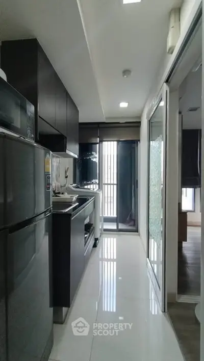 Modern kitchen with sleek appliances and glossy cabinets in a compact layout.