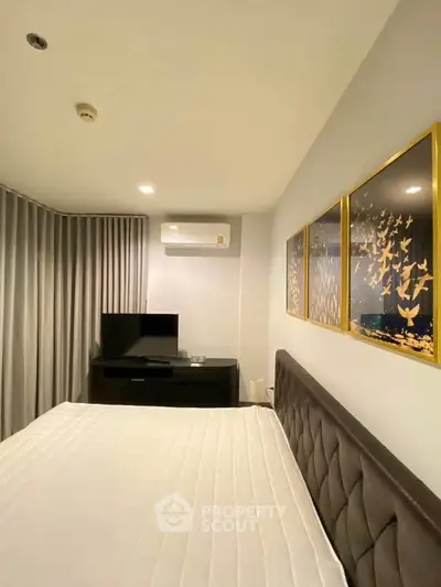 Modern bedroom with elegant decor and wall art, featuring a comfortable bed and sleek TV setup.