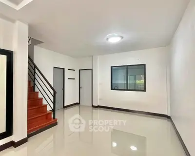 Spacious modern living room with glossy floors and staircase, ideal for family gatherings.