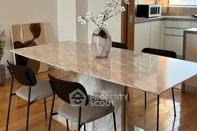Modern dining area with marble table and sleek kitchen in stylish apartment.