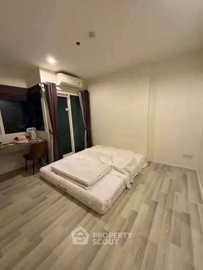 Spacious bedroom with minimalist decor and large window offering city views.