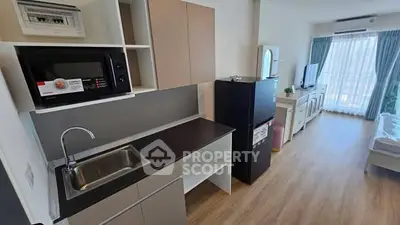 Modern studio apartment with sleek kitchen and cozy living area, featuring natural light and contemporary design.