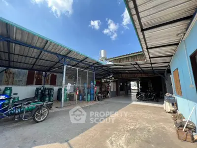 Spacious industrial property with covered storage and open area for vehicles.