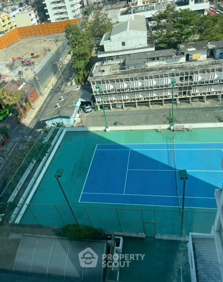 Stunning aerial view of urban tennis court surrounded by cityscape, perfect for sports enthusiasts.