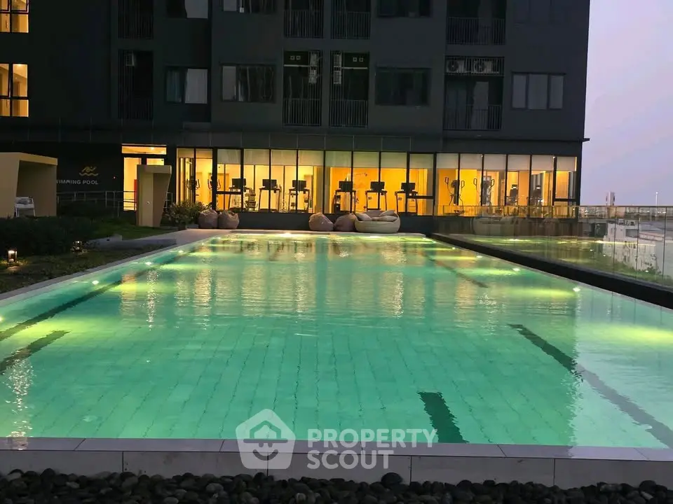 Luxurious apartment building with illuminated swimming pool and modern gym facilities.
