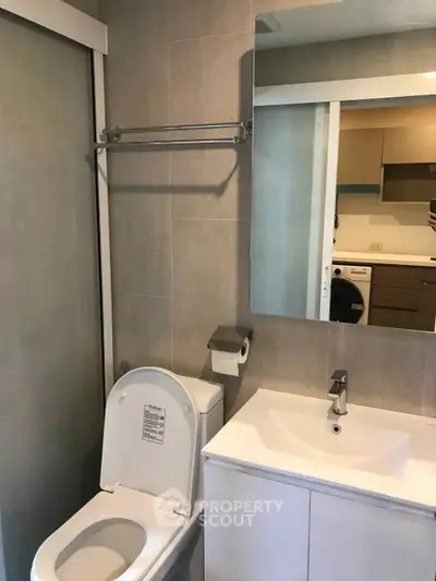 Modern bathroom with sleek fixtures and a glimpse of a contemporary kitchen