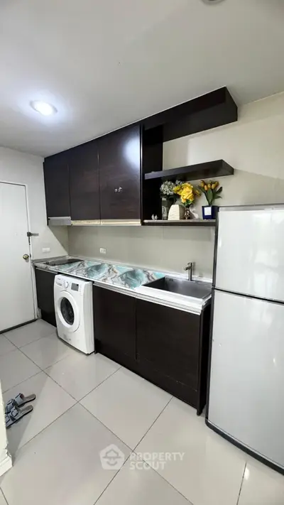 Modern kitchen with sleek cabinets, washing machine, and stainless steel fridge