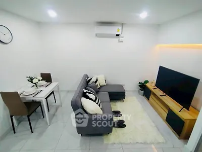 Modern living room with cozy sofa, TV, and dining area in a stylish apartment.