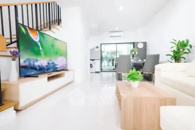Modern living room with large TV, elegant dining area, and stylish decor