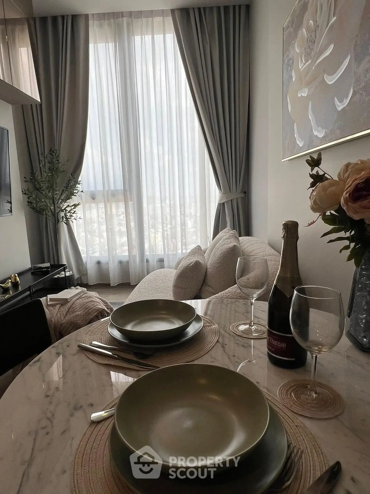 Elegant living room with cozy seating and dining area, featuring floor-to-ceiling windows and chic decor.