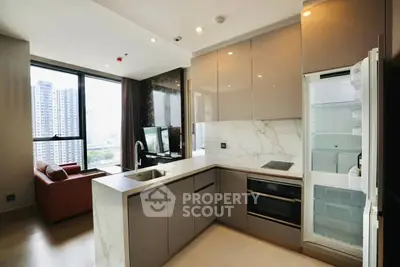 Modern open-layout kitchen with sleek appliances and spacious living area in high-rise apartment.
