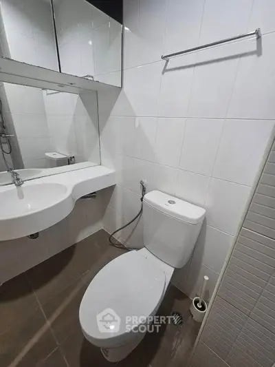 Modern bathroom with sleek white fixtures and large mirror