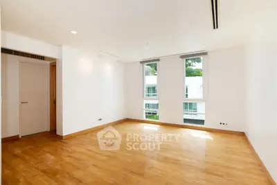 Spacious empty room with wooden flooring and large windows in modern apartment
