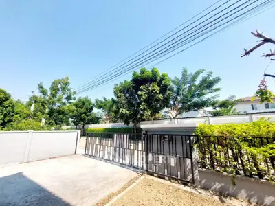 Spacious residential driveway with lush greenery and secure gate