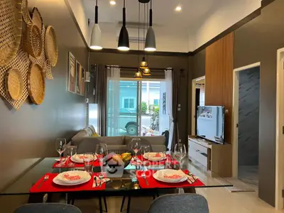 Modern living room with stylish decor and dining area, featuring elegant lighting and cozy seating.