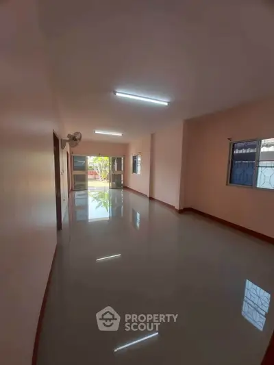 Spacious empty living room with glossy tiled floors and large windows.