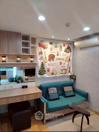 Cozy living room with modern decor and camping-themed wall art, featuring a teal sofa and stylish wooden furniture.