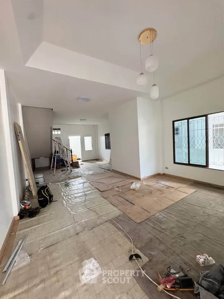 Spacious living room under renovation with modern lighting and large windows