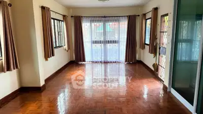 Spacious living room with polished wooden floors and large windows for natural light.