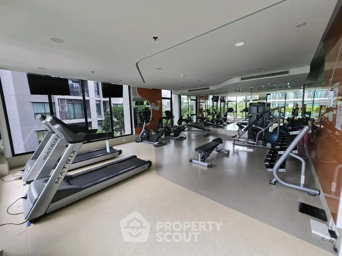 Modern gym with state-of-the-art equipment and large windows in a luxury apartment building.