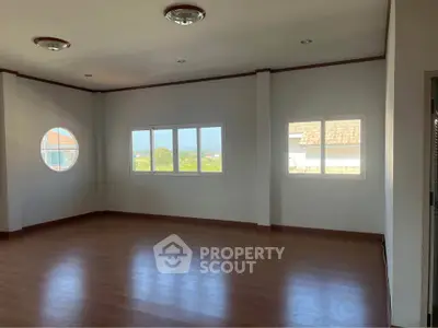 Spacious empty room with large windows and wooden flooring, perfect for customization.