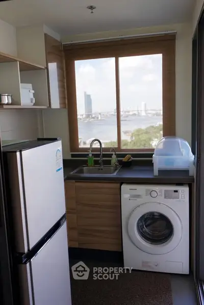 Modern kitchen with river view, featuring fridge and washing machine, ideal for urban living.