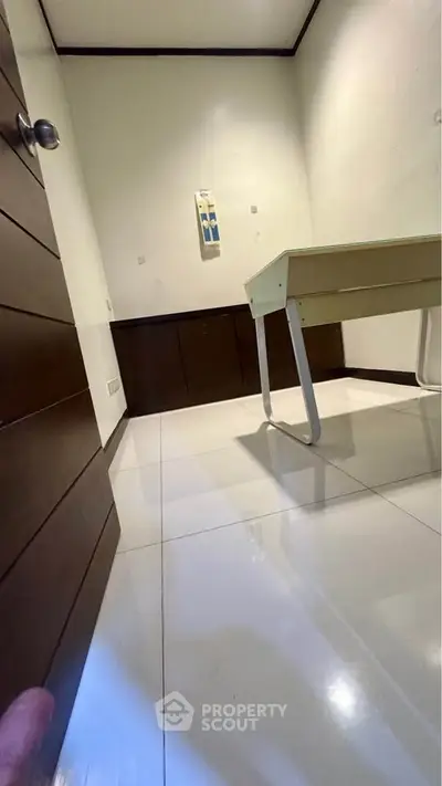 Minimalist study room with sleek desk and polished white tile flooring.