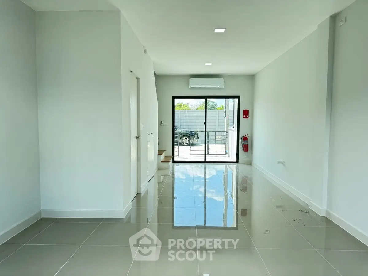 Spacious modern interior with glossy tiled floors and large glass doors leading to outdoor area.