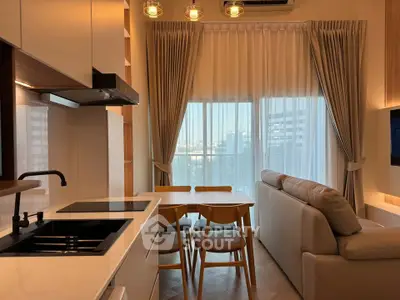 Modern open-layout kitchen and living room with natural light and stylish furnishings.