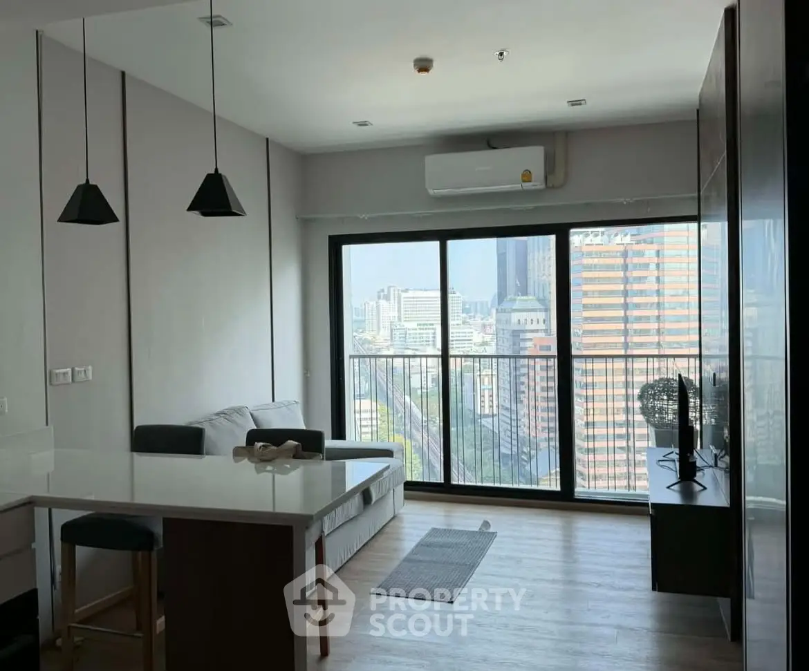 Modern living room with city view, featuring sleek furniture and large windows for natural light.
