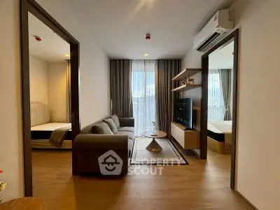 Modern living room with cozy sofa and TV, connecting to two bedrooms with natural light.
