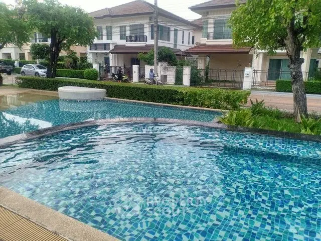 Charming residential pool with lush greenery and modern houses in the background.