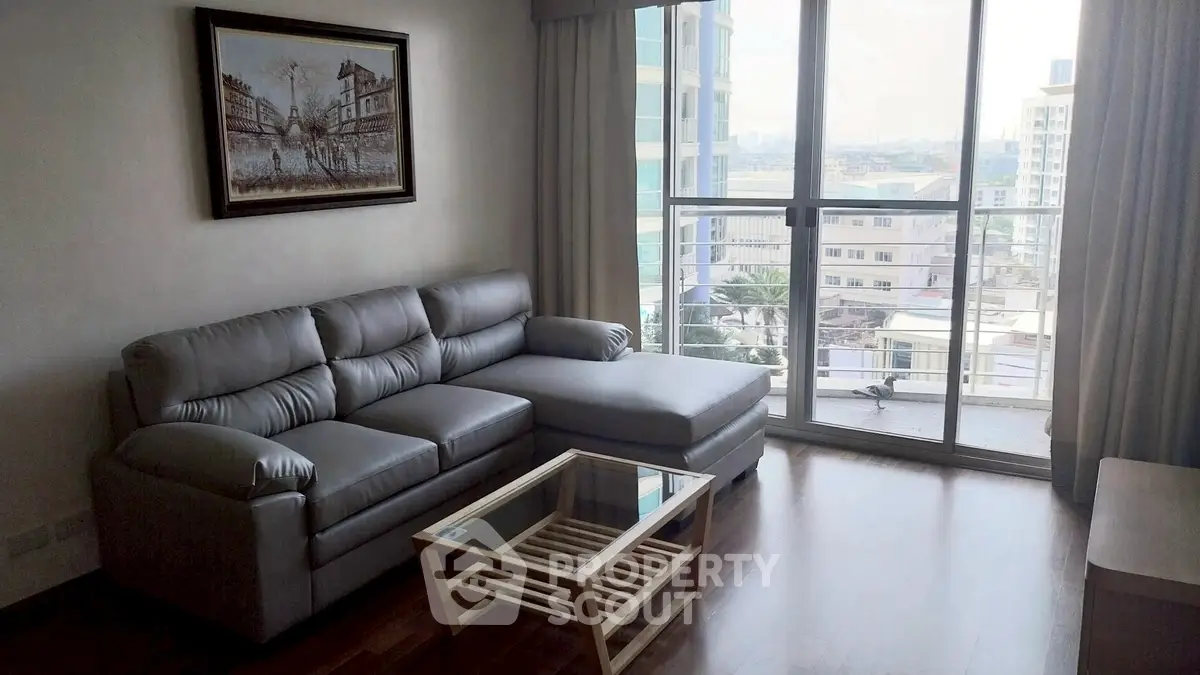 Spacious living room with modern sofa and city view balcony.