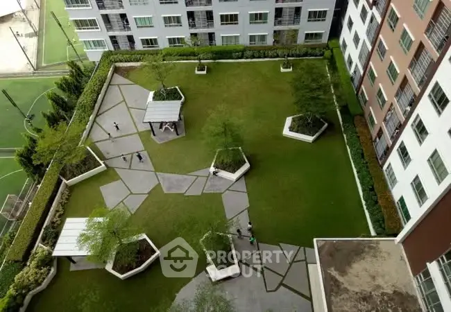 Aerial view of modern apartment complex with landscaped garden and walking paths.