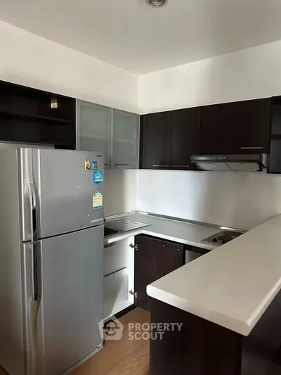 Modern kitchen with sleek cabinets and stainless steel fridge in a cozy apartment.