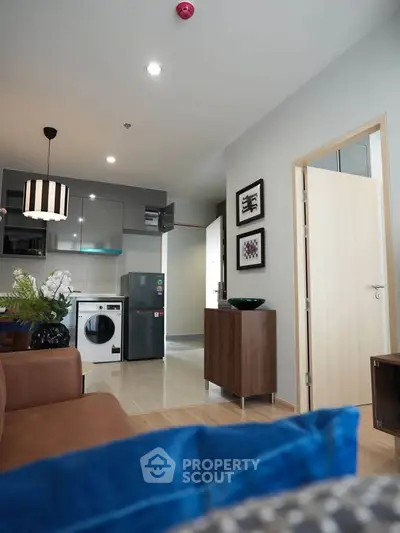 Modern living room with open kitchen, featuring sleek appliances and stylish decor.