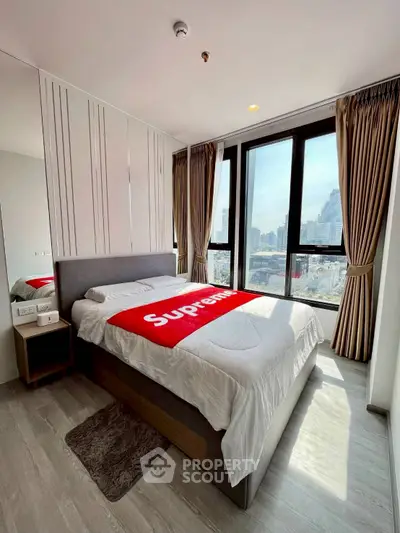Modern bedroom with city view, featuring large windows and stylish decor.