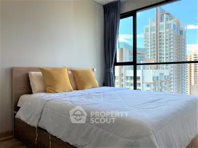 Modern bedroom with large window offering stunning city view in high-rise apartment.