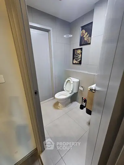 Modern bathroom with sleek design and stylish decor, featuring a toilet and contemporary wall art.