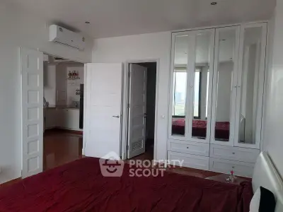 Spacious bedroom with mirrored wardrobe and city view, featuring modern air conditioning and elegant decor.