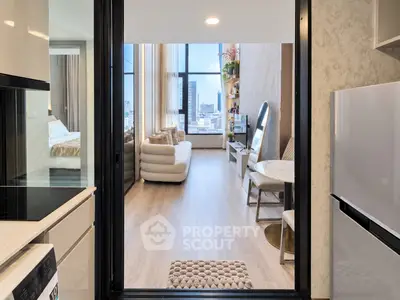 Modern apartment interior with open kitchen and cozy living room, featuring large windows and city view.