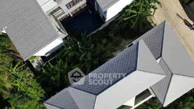 Aerial view of modern building with lush greenery and sleek roof design.