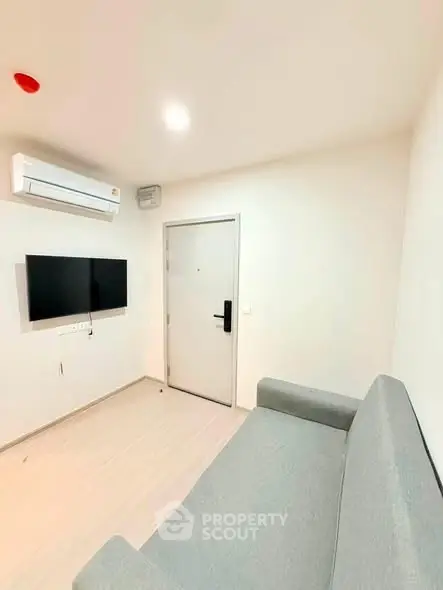 Modern minimalist living room with sleek sofa and wall-mounted TV, perfect for cozy relaxation.