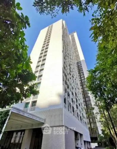 Stunning high-rise building surrounded by lush greenery and clear blue sky.