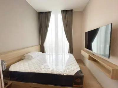 Modern bedroom with large window, stylish curtains, and wall-mounted TV in a cozy apartment.