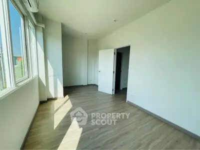 Bright empty room with wooden flooring and large windows